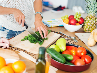 Woman at kitchen counter chopping vegetables.