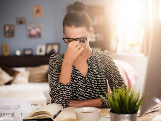 Woman sitting at desk, feeling fatigued.